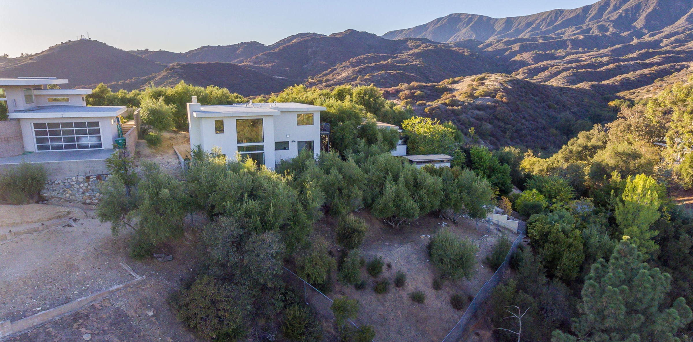 Aerial photograph at golden hour of a modern hillside home framed by the San Bernardino mountains